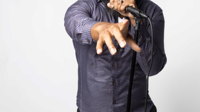 jclay-holding-a-mic-gazing-into-camera_WEB